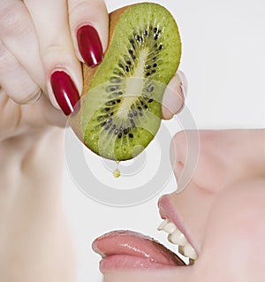 Woman squeezing kiwi into mouth