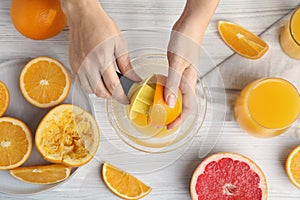 Woman squeezing orange juice at wooden table, top view