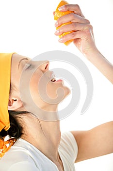 Woman squeezing orange into mouth