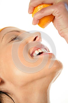 Woman squeezing orange into mouth