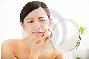 woman Squeezing pimple looking on mirror photo