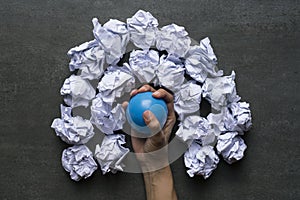 Woman squeezing a stress ball with crumpled paper