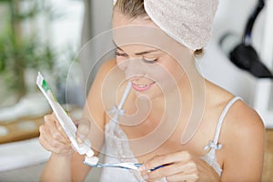 woman squeezing toothpaste onto toothbrush in bathroom photo