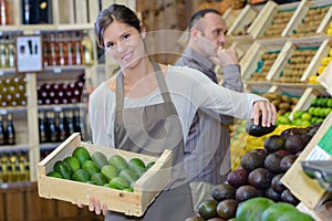 Woman stacking avocados in greengrocers