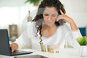 woman with stacks coins using laptop