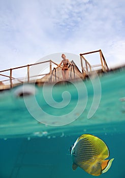Woman on the stairs at descent to the sea and a under water view, person is visible through water drops