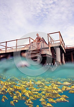 Woman on the stairs at descent to the sea and a under water view, person is visible through water drops