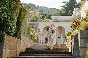 Woman on the stairs in the park. A middle-aged lady in a hat in a white outfit with a bag walks around the Livadia