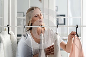 Woman stand behind rack with outfit, choosing stylish wear photo