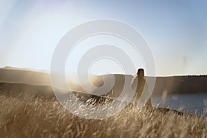 A woman stand on dried Grass flower in meadow with sun lights