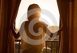 Woman stand in the room open curtain see sunrise