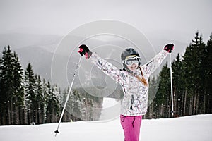 Woman stand skiing, is preparing descend down on snow track in Carpathian mountains. On background forest and ski slopes. Winter