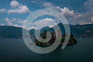 Woman stand up padling beside castle on the island Isola di Loreto on Lake Iseo, Italy