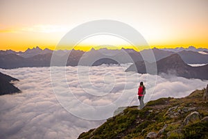 A woman standing above the clouds watching the sun rise