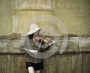 Woman standing againg on the wall and playing violin ,model posing