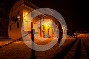 Woman standing in Alghero promenade at night