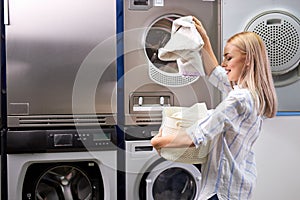 woman standing alone with clean towels in the self serviced laundry with dryer machines