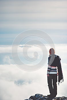 Woman standing alone on cliff over clouds