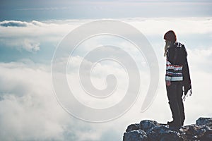 Woman standing alone on cliff over clouds landscape