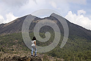 Woman standing alone on a rock looking at the blue mountains nature scenery. Happiness, strength and freedom lifestyle