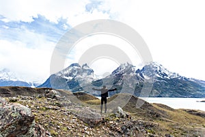 woman standing with arms wide open with Torres del Paine mountain range in the background