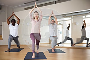 Woman standing in Ashta Chandrasana with hands in namaste over head