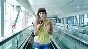 Woman standing on Automatic walkway, stairs in subway crossing, using her phone, a mean of communication, a fashionable