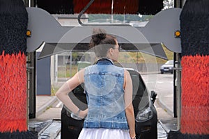 Woman standing back in front of car, car washing process