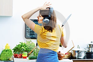 Woman standing back in kitchen, cooking healthy food with fun a