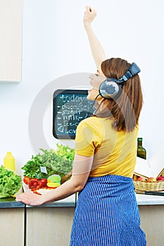 Woman standing back in kitchen, cooking healthy food with fun a