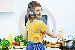 Woman standing back in kitchen, cooking healthy food with fun a