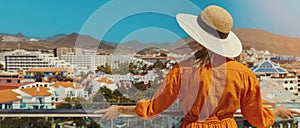 woman standing on balcony and enjoying view to the Playa de las Americas holiday resort skyline in Tenerife. copy