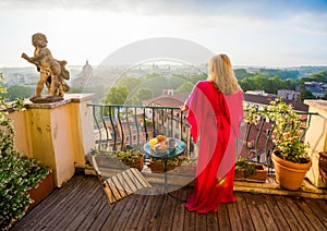 Woman standing on balcony and overlooking city in morning