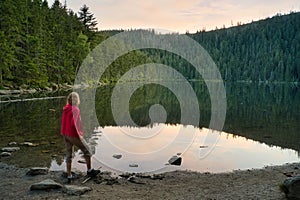 A woman standing on the bank of beautiful Devil`s Lake in the Bohemian Forest, Czech Republic