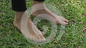 A woman standing barefoot on grass and feeling the nature