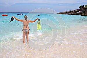 Woman standing at the beach holding snorkel gear