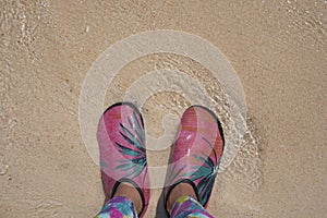 Woman standing on the beach sand and wearing wading shoes, beach of Krabi