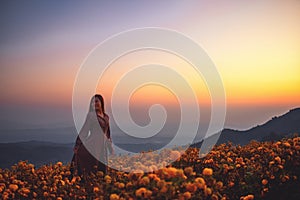 A woman standing among beautiful flower garden on the top of the hill before sunriseSilhouette image of a