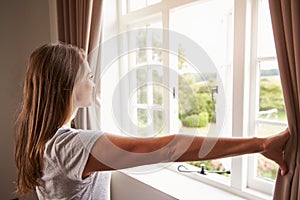 Una mujer de pie de acuerdo a dormitorio a a partir de cortinas 