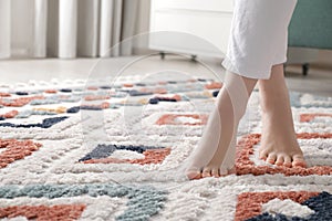 Woman standing on carpet with pattern at home, closeup. Space for text