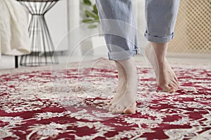 Woman standing on carpet with pattern at home, closeup. Space for text