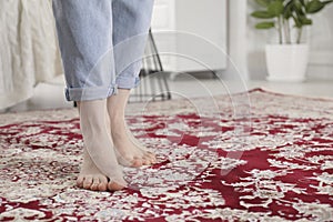 Woman standing on carpet with pattern at home, closeup. Space for text