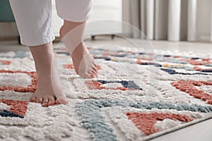 Woman standing on carpet with pattern at home, closeup. Space for text