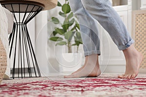 Woman standing on carpet with pattern at home, closeup. Space for text