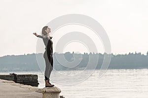 Woman standing on a cement bollard on a quay