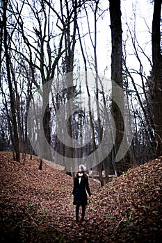 Woman standing in dark cold forest background