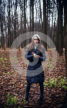 Woman standing in dark cold forest background