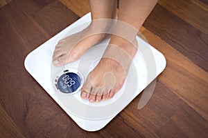 Woman standing on a digital scale with body fat analyzer