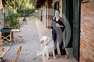 Woman standing with dog and looking away near entrance to hotel room