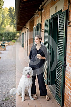 Woman standing with dog and looking away near entrance to hotel room